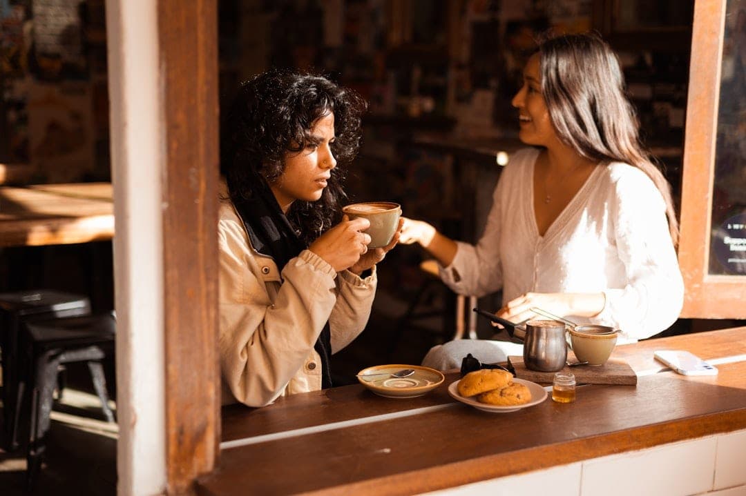 A diverse group of people gathered around a table, laughing and connecting in warm light